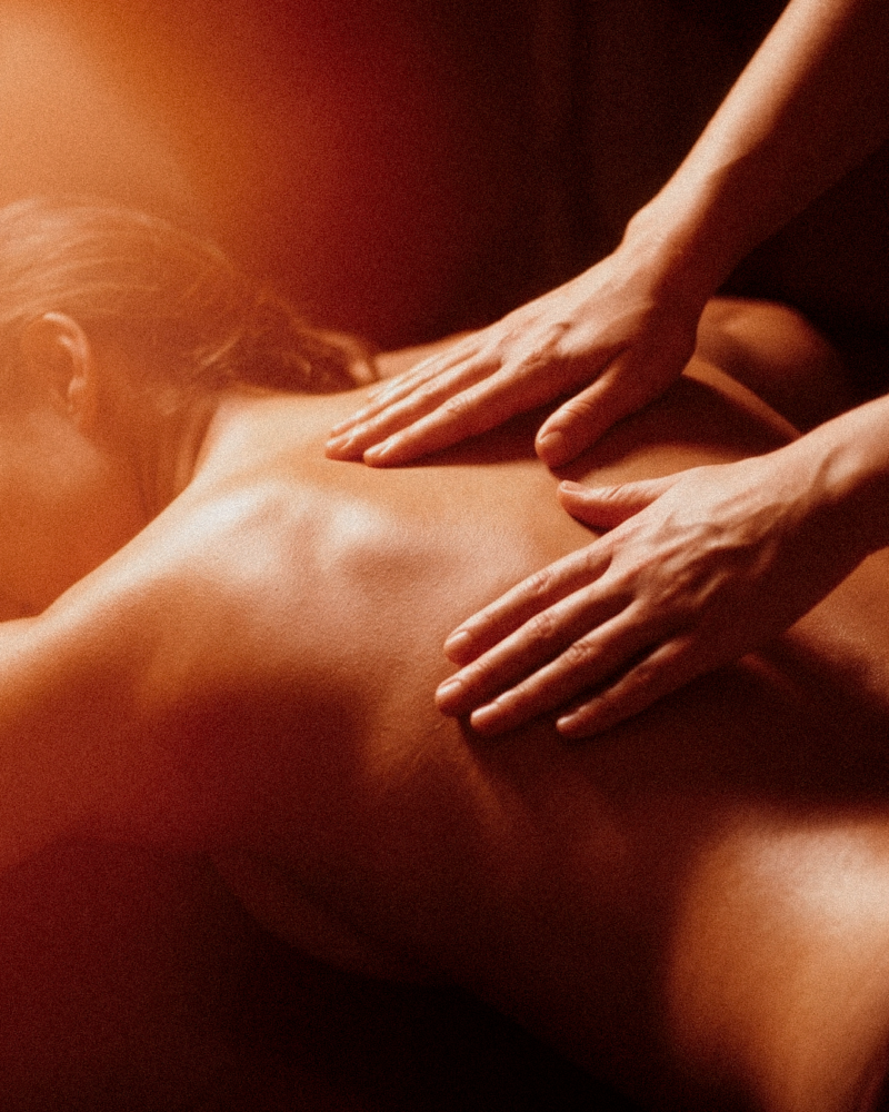 Massatge Californian Fusion a Nature Girona: mans expertes treballant l'esquena amb moviments fluids i llum càlida.
