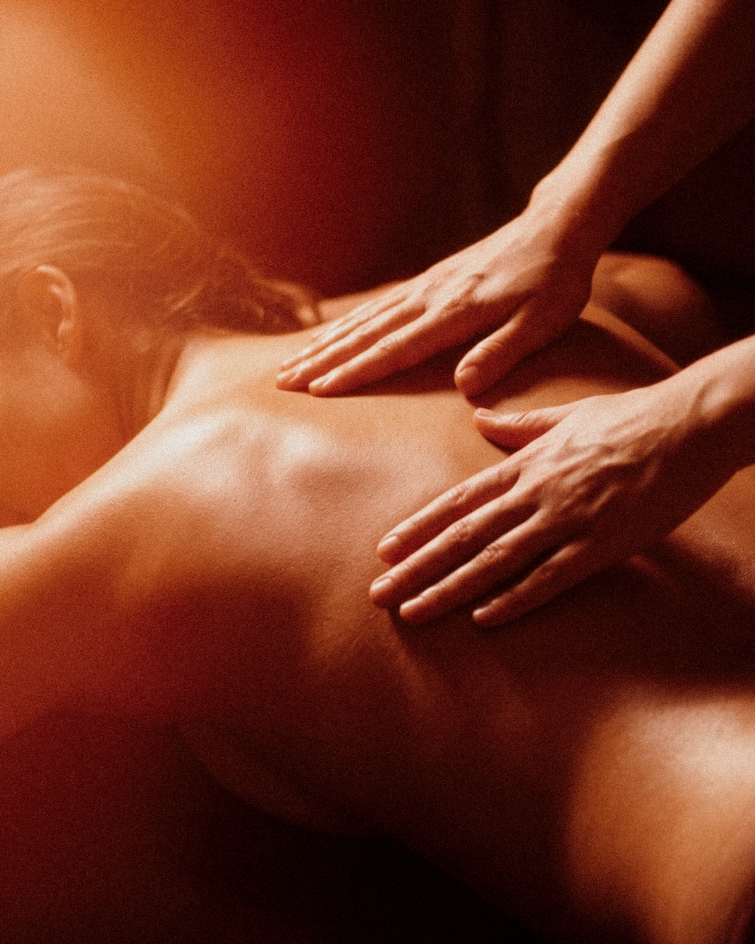 Massatge Californian Fusion a Nature Girona: mans expertes treballant l'esquena amb moviments fluids i llum càlida.